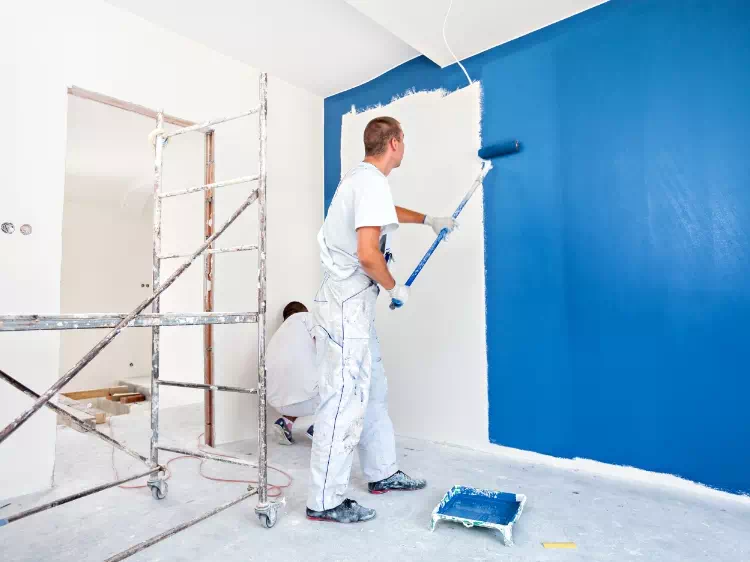 mężczyzna malujący ścianę na niebiesko
